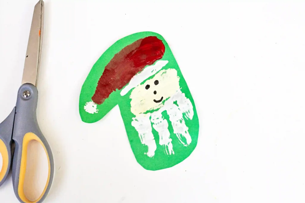 Handprint Santa Ornament - Cultivating Brilliant Minds a handprint made to look like santa on green construction paper