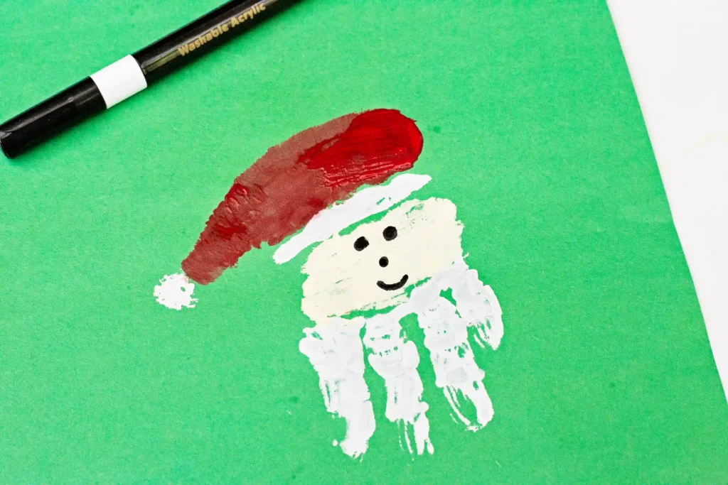 Handprint Santa Ornament - Cultivating Brilliant Minds a handprint made to look like santa on green construction paper