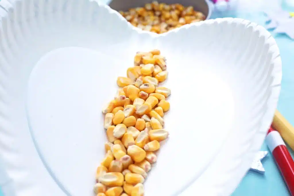 Paper Plate Noisemaker Craft - Cultivating Brilliant Minds a paper plate being folded with corn inside