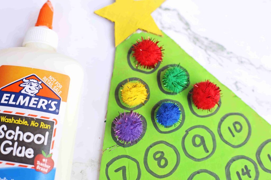 Christmas Tree Countdown Craft - Cultivating Brilliant Minds cardboard painted to look like a christmas tree with numbers on it. Pom poms are glued over some of the numbers