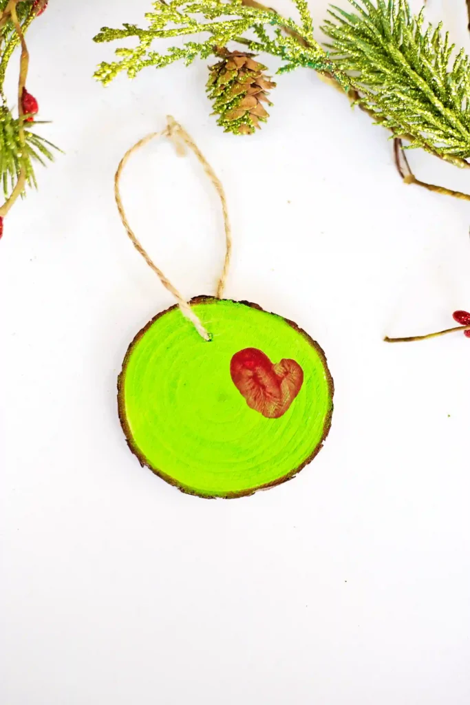 Grinch Heart Wood Slice Ornament Craft - Cultivating Brilliant Minds a wood slice ornament decorated to look like the grinch's heart