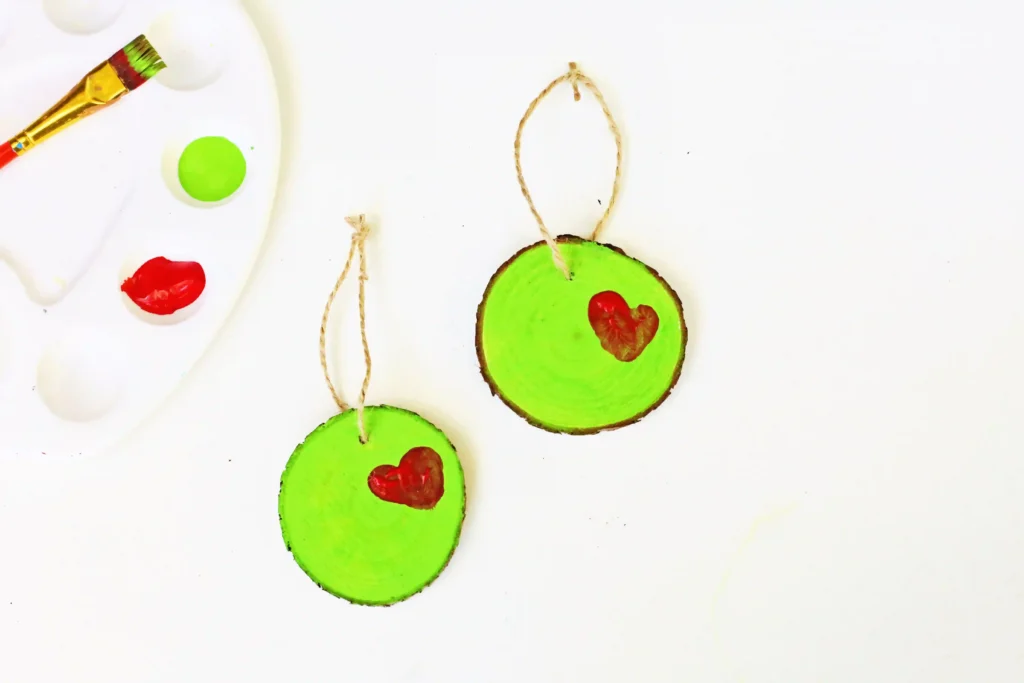 Grinch Heart Wood Slice Ornament Craft - Cultivating Brilliant Minds a wood slice ornament decorated to look like the grinch's heart