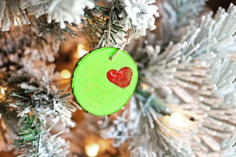a wood slice ornament on a tree decorated to look like the grinch's heart