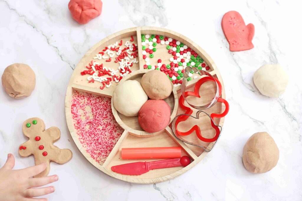 Holiday Cookie Playdough Bakery Tray - Cultivating Brilliant Minds a playdough tray filled with holiday-related items like red and green sprinkles and gingerbread cookie cutters