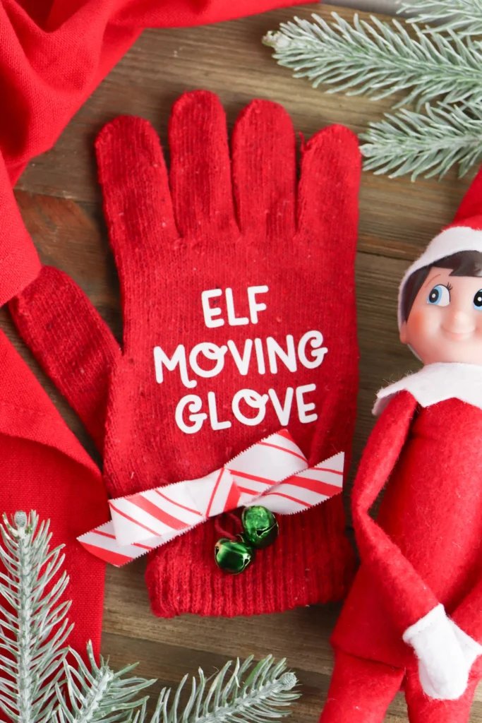 and elf on the shelf next to a red glove that says "elf moving glove"