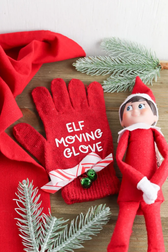 and elf on the shelf next to a red glove that says "elf moving glove"