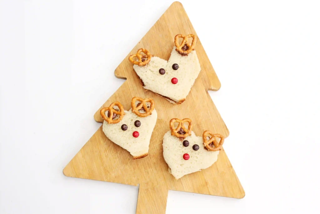 Nutella Reindeer Sandwiches - Cultivating Brilliant Minds a nutella sandwich decorated with m&ms and pretzels to look like a reindeer