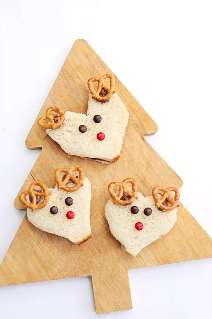 Nutella Reindeer Sandwiches - Cultivating Brilliant Minds a nutella sandwich decorated with m&ms and pretzels to look like a reindeer
