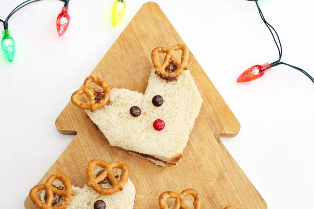 Nutella Reindeer Sandwiches - Cultivating Brilliant Minds a nutella sandwich decorated with m&ms and pretzels to look like a reindeer