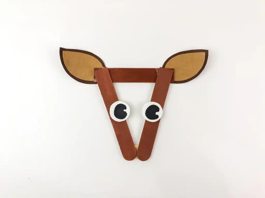 Reindeer Popsicle Stick Ornament Craft - Cultivating Brilliant Minds popsicle sticks painted brown arranged into a triangle with reindeer ears and eyes