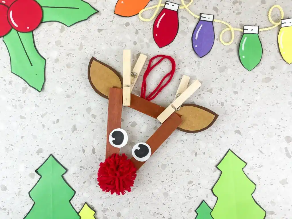 Reindeer Popsicle Stick Ornament Craft - Cultivating Brilliant Minds an ornament craft made of popsicle sticks that looks like a reindeer