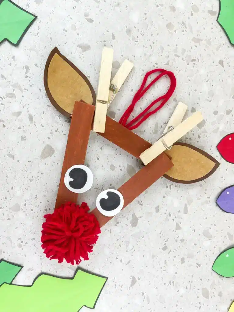 Reindeer Popsicle Stick Ornament Craft - Cultivating Brilliant Minds an ornament craft made of popsicle sticks that looks like a reindeer