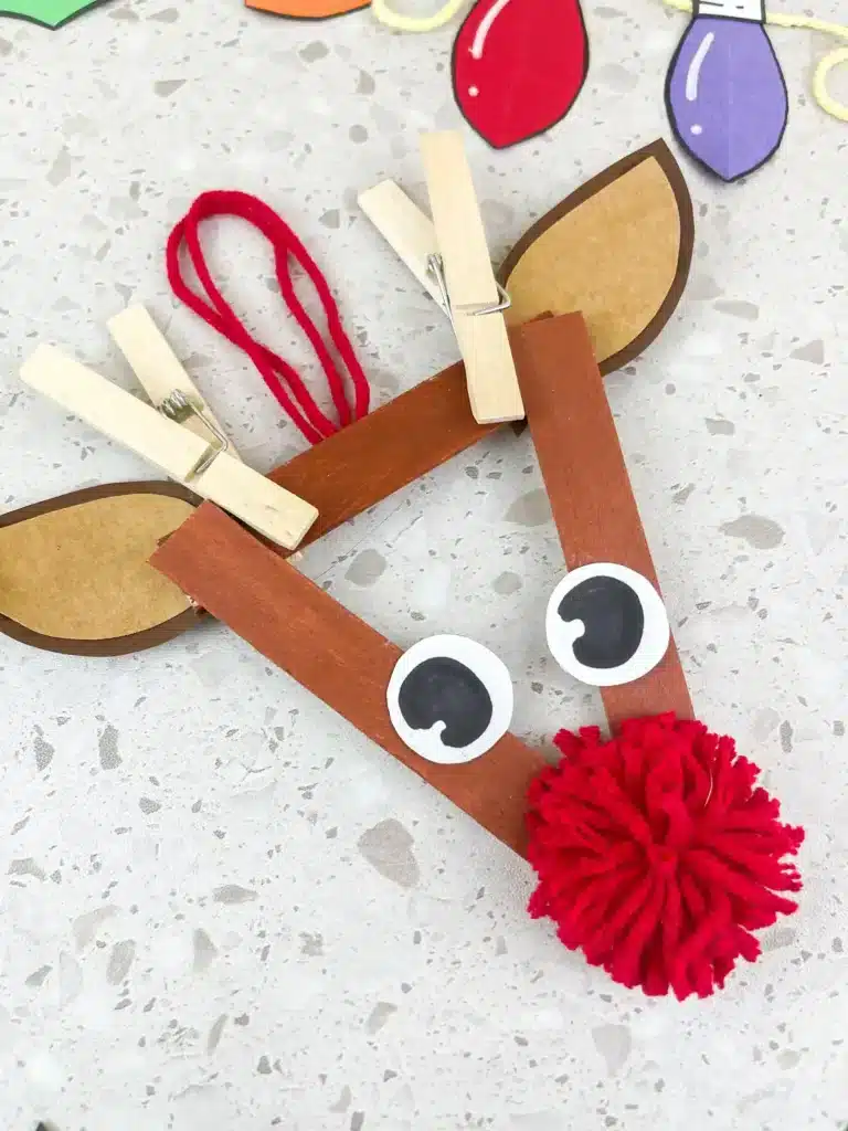 Reindeer Popsicle Stick Ornament Craft - Cultivating Brilliant Minds an ornament craft made of popsicle sticks that looks like a reindeer