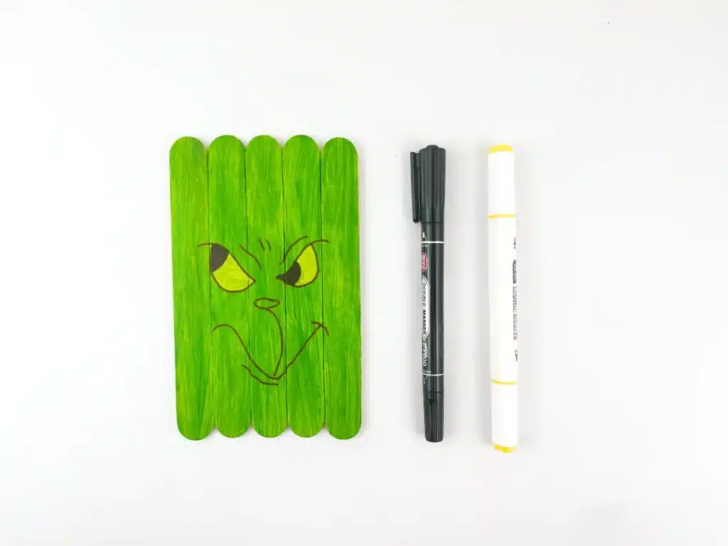 Grinch Popsicle Stick Craft - Cultivating Brilliant Minds popsicle sticks glued together and painted green with a grinch face