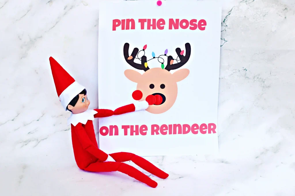 Pin the Nose on the Reindeer - Cultivating Brilliant Minds an elf on the shelf next to red dot stickers and a sign that reads "pin the nose on the reindeer"