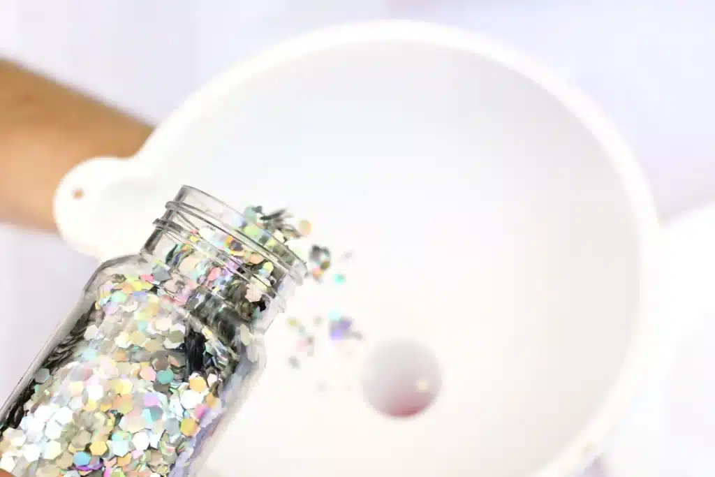 Candy Cane Sensory Wand - Cultivating Brilliant Minds adding glitter into a funnel