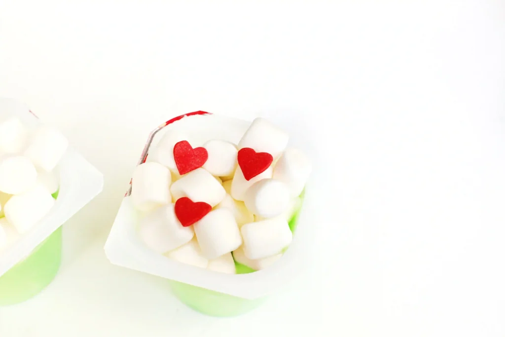 Grinch Pudding - Cultivating Brilliant Minds a vanilla pudding cup dyed green with marshmallows and candy hearts