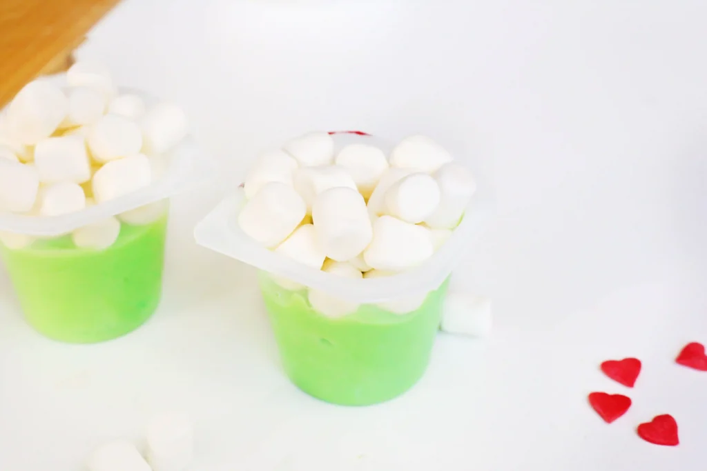 Grinch Pudding - Cultivating Brilliant Minds vanilla pudding cups dyed green with mini marshmallows on top