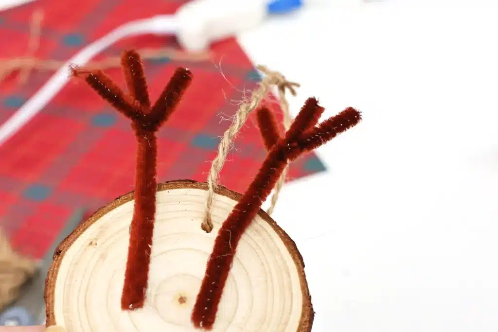 Rudolph Wood Slice Ornament - Cultivating Brilliant Minds wood slice with brown pipe cleaner antlers and string to create an ornament