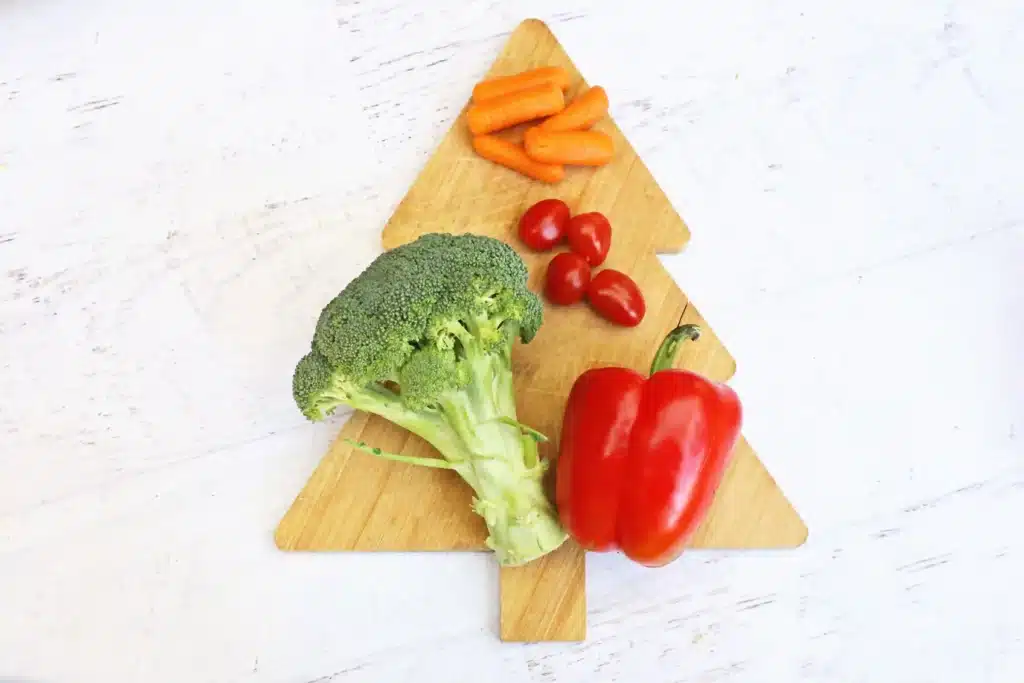 Christmas Tree Veggie Tray - Cultivating Brilliant Minds broccoli, red bell pepper, cherry tomatoes, and carrots on a wooden cutting board shaped like a christmas tree