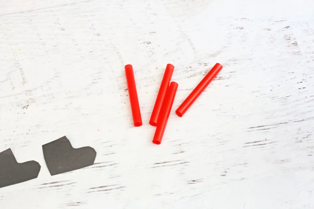 Santa in the Chimney Pudding Snack - Cultivating Brilliant Minds cut straw next to boots cut out of black construction paper