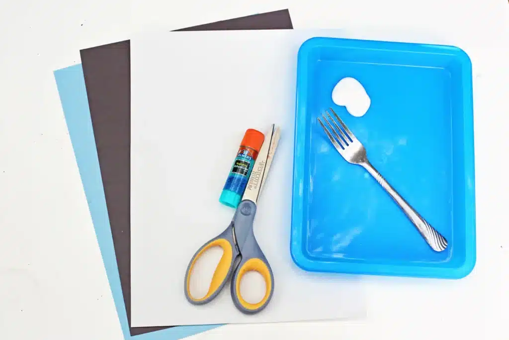 Fork Painted Abominable Snowman - Cultivating Brilliant Minds black, white, and blue construction paper, glue, scissors, a fork, and white paint on a blue tray