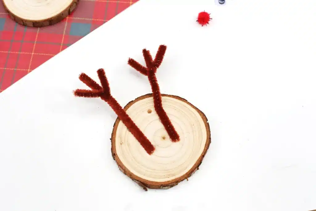 Rudolph Wood Slice Ornament - Cultivating Brilliant Minds a wood slice with brown pipe cleaner antlers attached