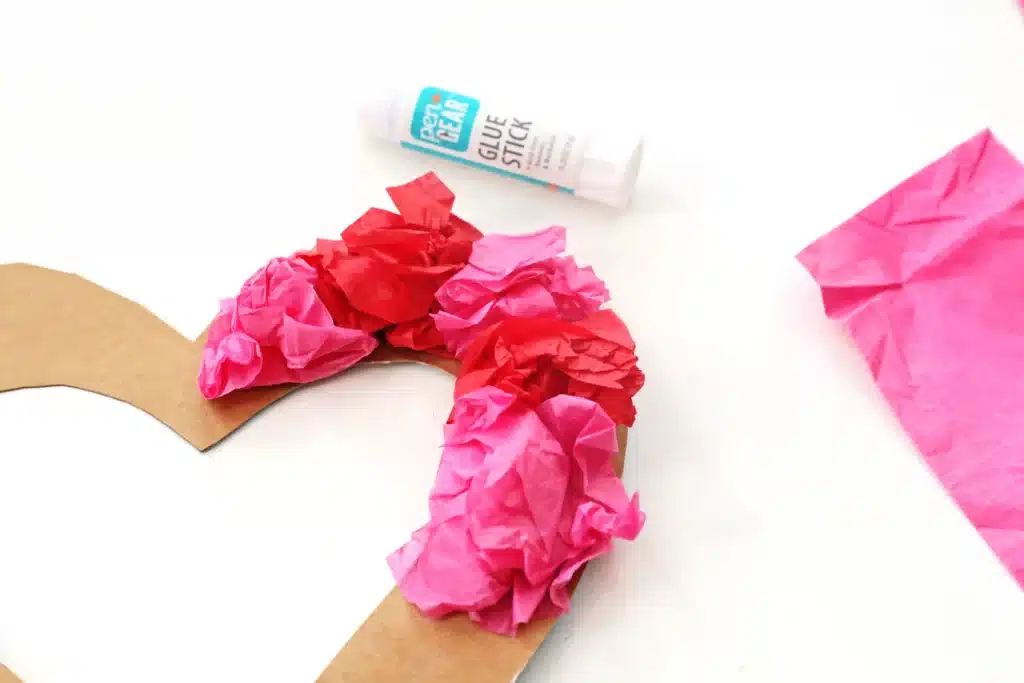 Tissue Paper Heart Wreath - Cultivating Brilliant Minds gluing tissue paper on the cardboard heart