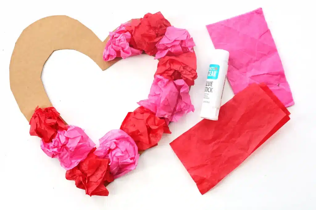 Tissue Paper Heart Wreath - Cultivating Brilliant Minds gluing tissue paper on the cardboard heart