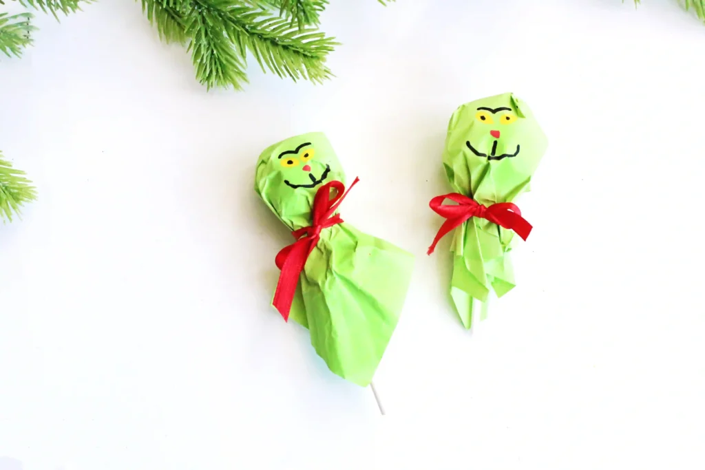 Grinch Lollipops - Cultivating Brilliant Minds a lollipop covered with green tissue paper and decorated to look like the grinch