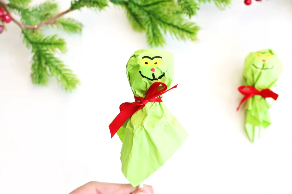 Grinch Lollipops - Cultivating Brilliant Minds grinch lollipops: a lollipop covered with green tissue paper and decorated to look like the grinch