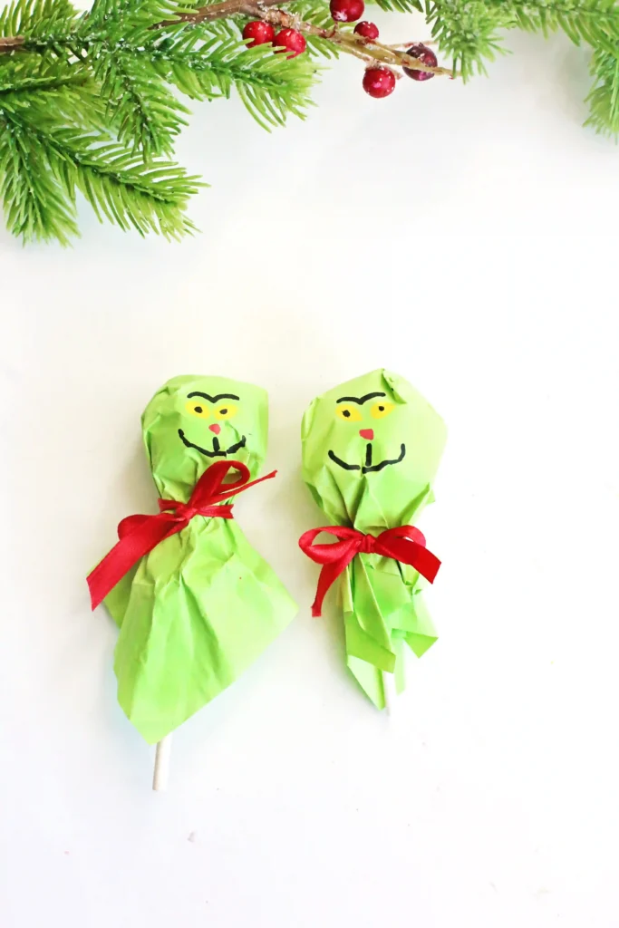 Grinch Lollipops - Cultivating Brilliant Minds a lollipop covered with green tissue paper and decorated to look like the grinch