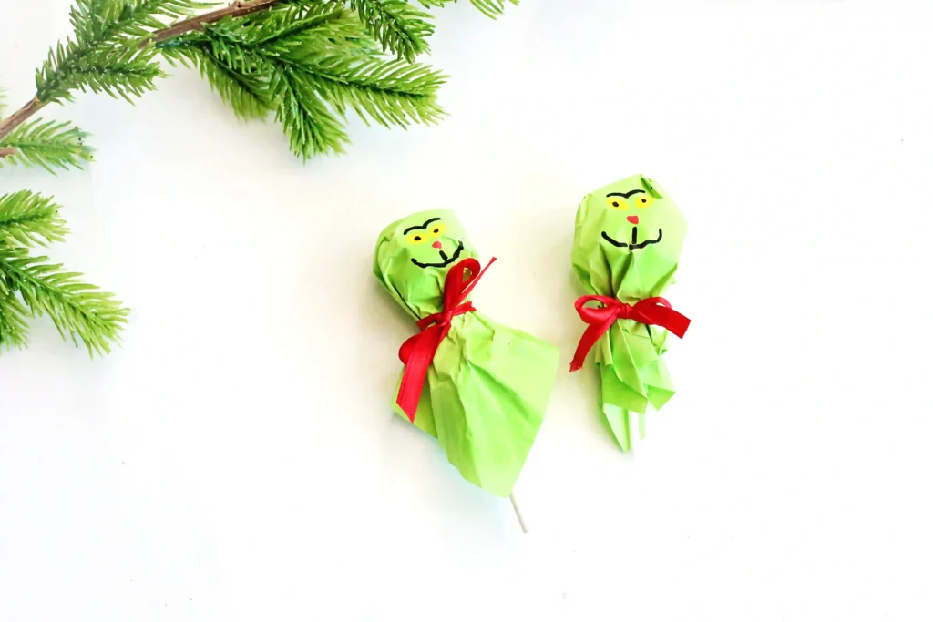 Grinch Lollipops - Cultivating Brilliant Minds a lollipop covered with green tissue paper and decorated to look like the grinch