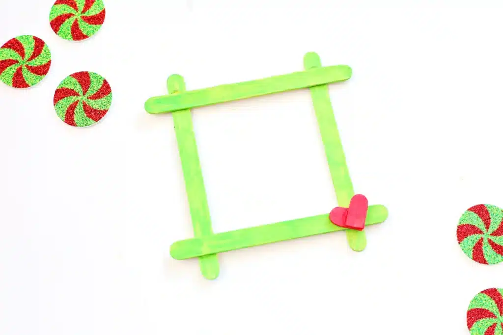 Grinch Popsicle Stick Photo Frame - Cultivating Brilliant Minds a photo frame made from popsicle sticks painted red and green for the grinch