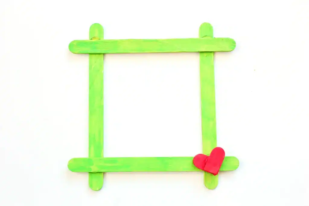 Grinch Popsicle Stick Photo Frame - Cultivating Brilliant Minds a photo frame made from popsicle sticks painted red and green for the grinch