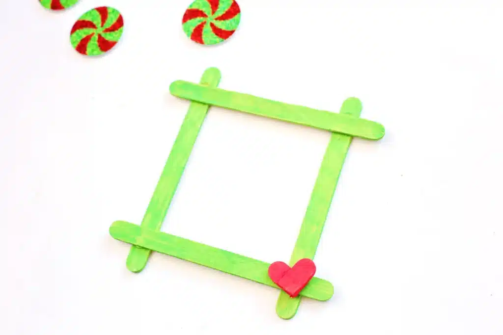 Grinch Popsicle Stick Photo Frame - Cultivating Brilliant Minds a photo frame made from popsicle sticks painted red and green for the grinch