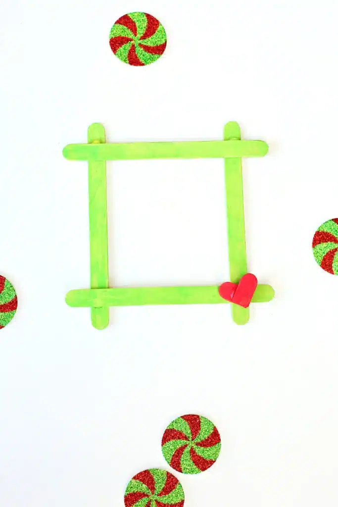 Grinch Popsicle Stick Photo Frame - Cultivating Brilliant Minds a photo frame made from popsicle sticks painted red and green for the grinch