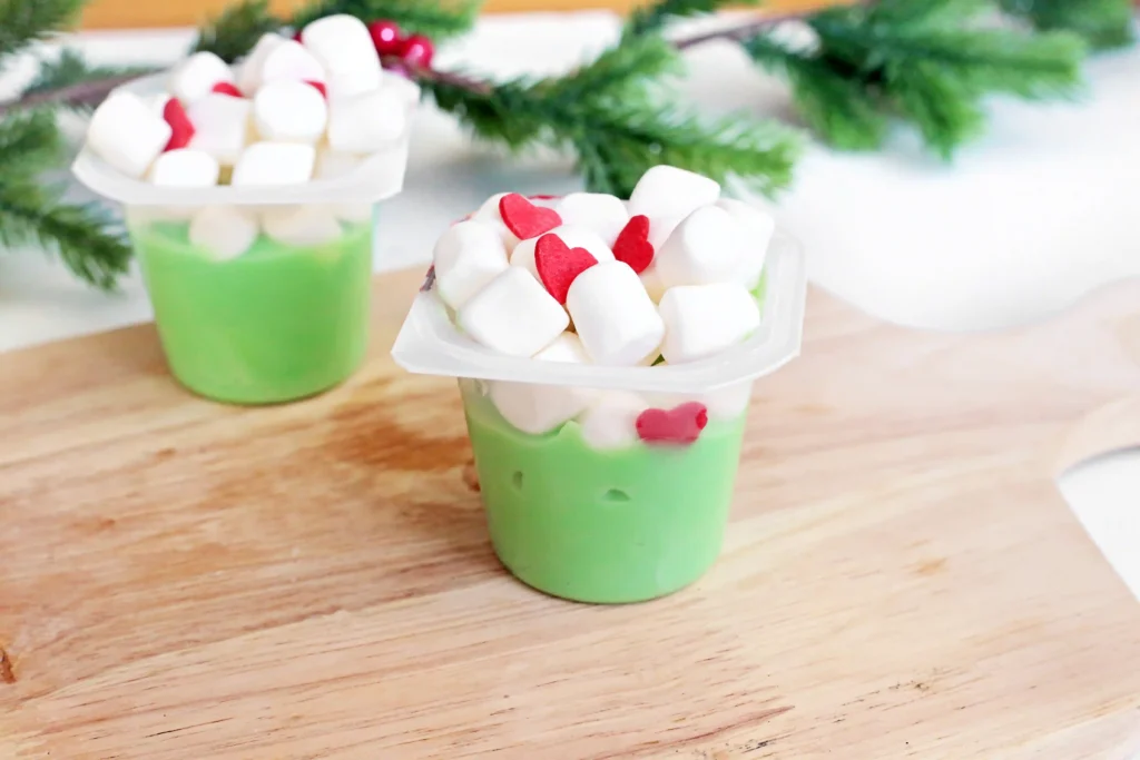 Grinch Pudding - Cultivating Brilliant Minds a vanilla pudding cup dyed green with marshmallows and candy hearts
