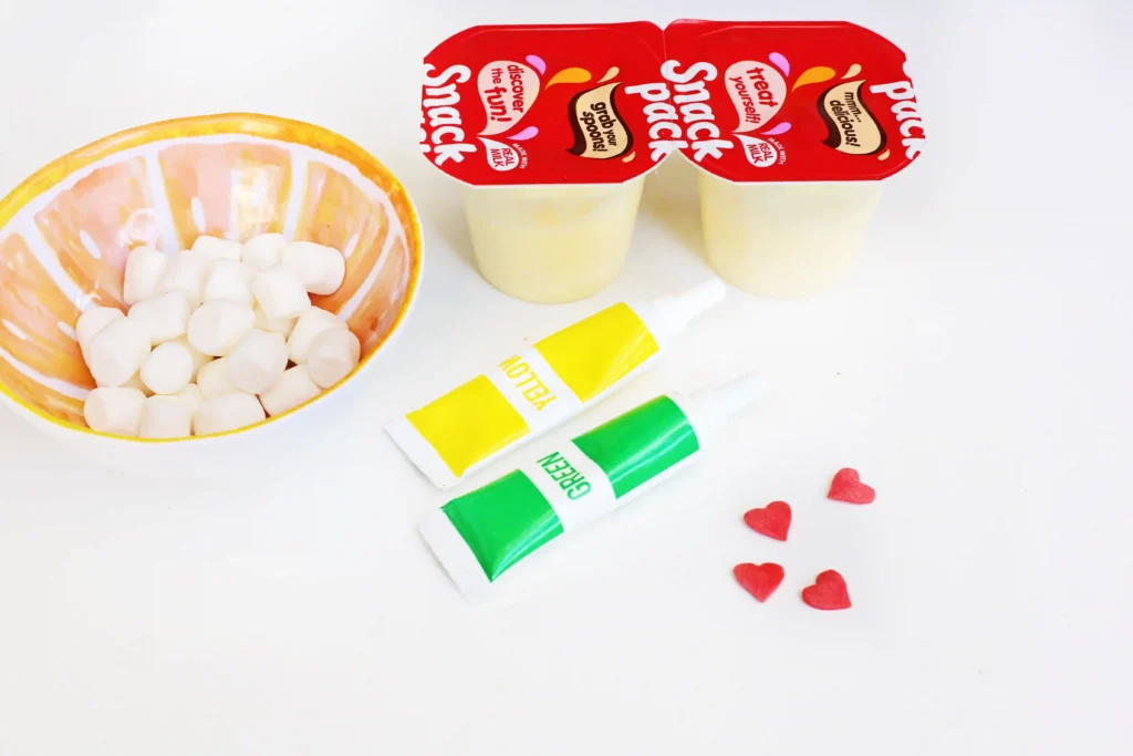 Grinch Pudding - Cultivating Brilliant Minds grinch pudding cups: vanilla pudding cups, mini marshmallows, candy hearts, and yellow and green food coloring