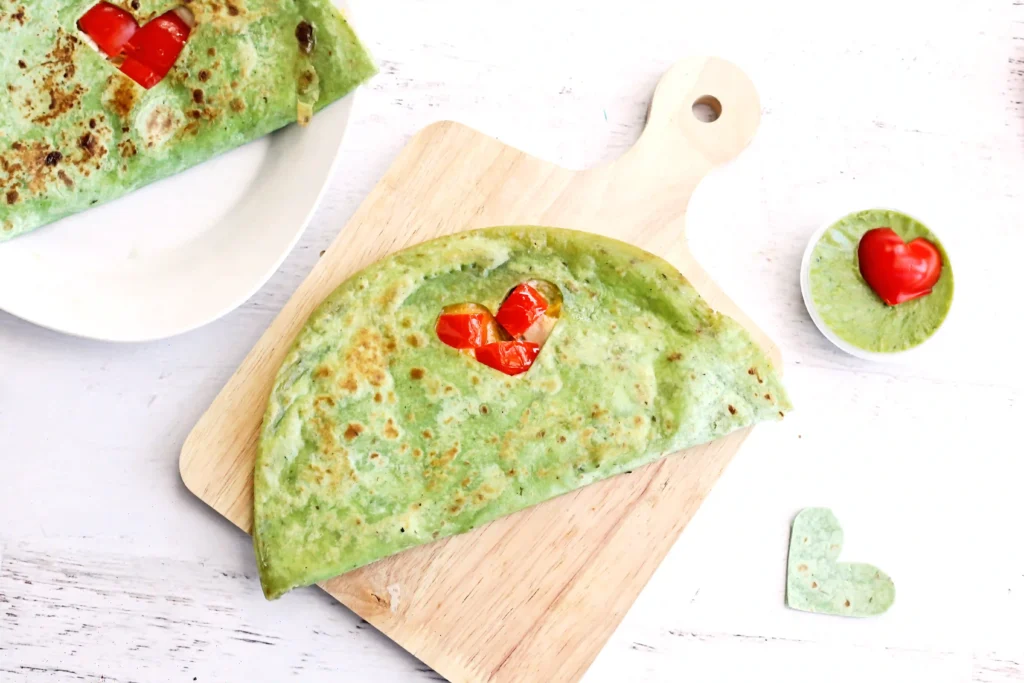 Grinch Quesadillas - Cultivating Brilliant Minds a quesadilla with a heart cut out and red peppers inside