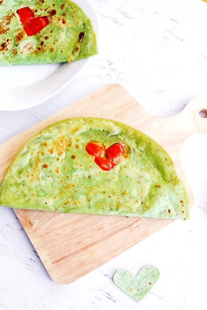 Grinch Quesadillas - Cultivating Brilliant Minds a quesadilla with a heart cut out and red peppers inside