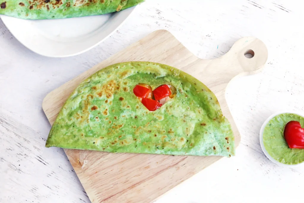 Grinch Quesadillas - Cultivating Brilliant Minds a quesadilla with a heart cut out and red peppers inside
