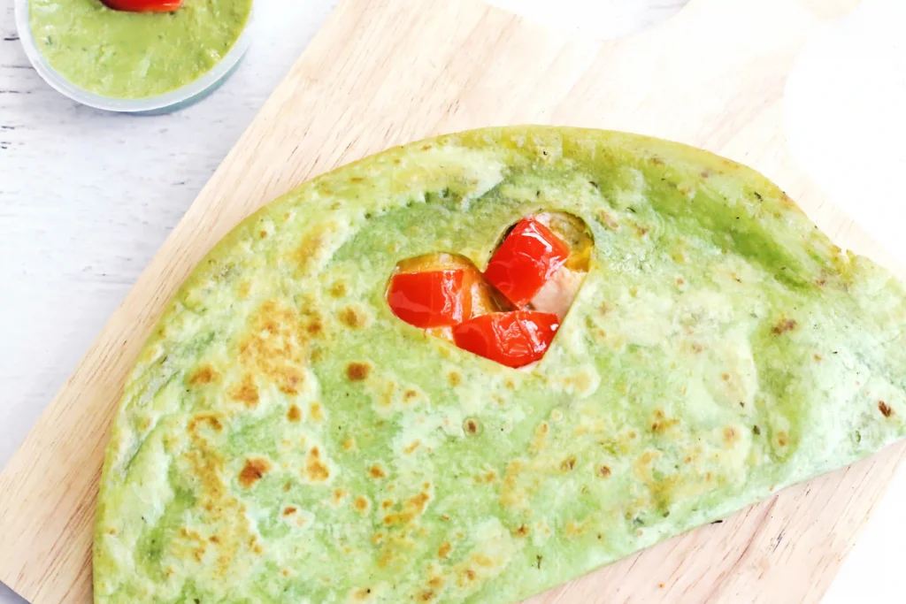 Grinch Quesadillas - Cultivating Brilliant Minds a quesadilla with a heart cut out and red peppers inside