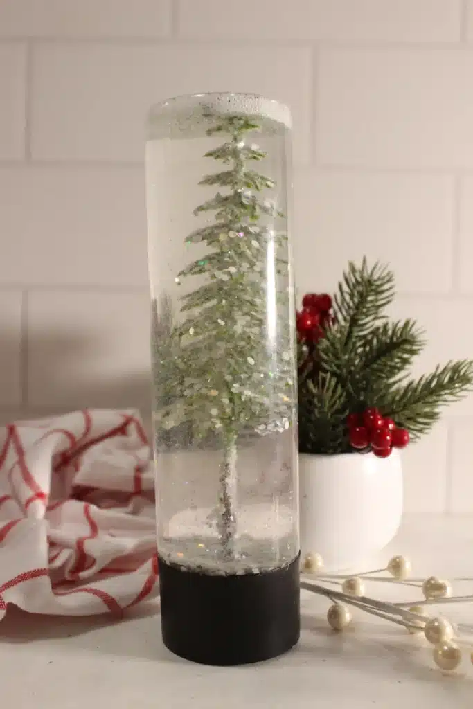 Snow Globe Sensory Bottle - Cultivating Brilliant Minds a snow globe sensory bottle with a christmas tree inside