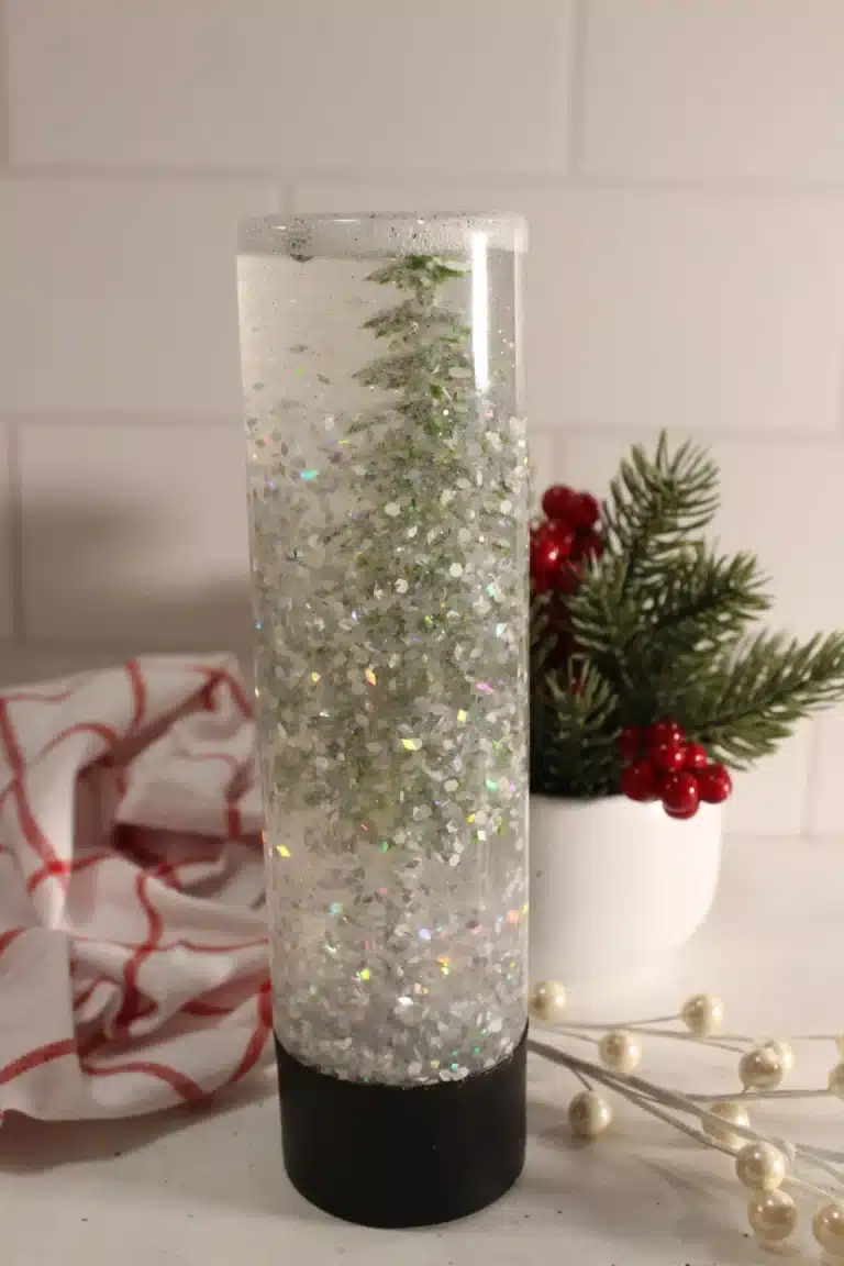 a snow globe sensory bottle with a christmas tree inside