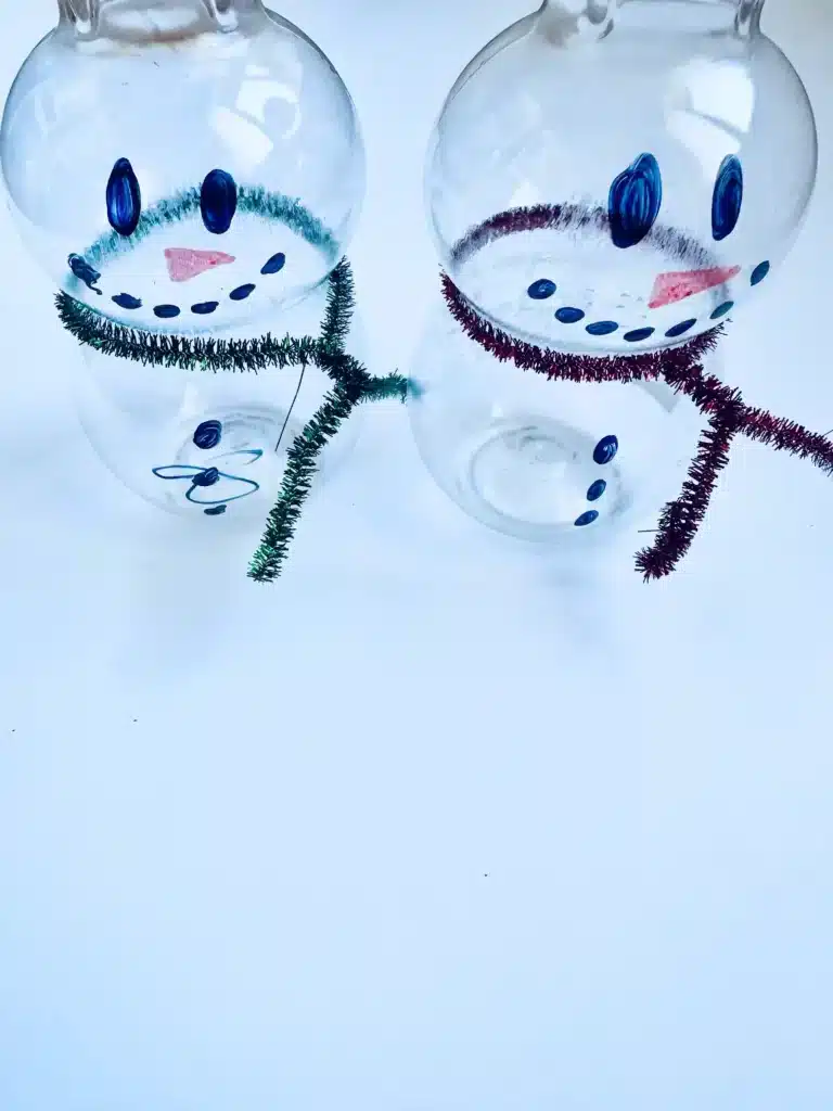 Snowman Sensory Bin - Cultivating Brilliant Minds an empty plastic bottle with a face drawn on and a pipe cleaner scarf to look like a snowman