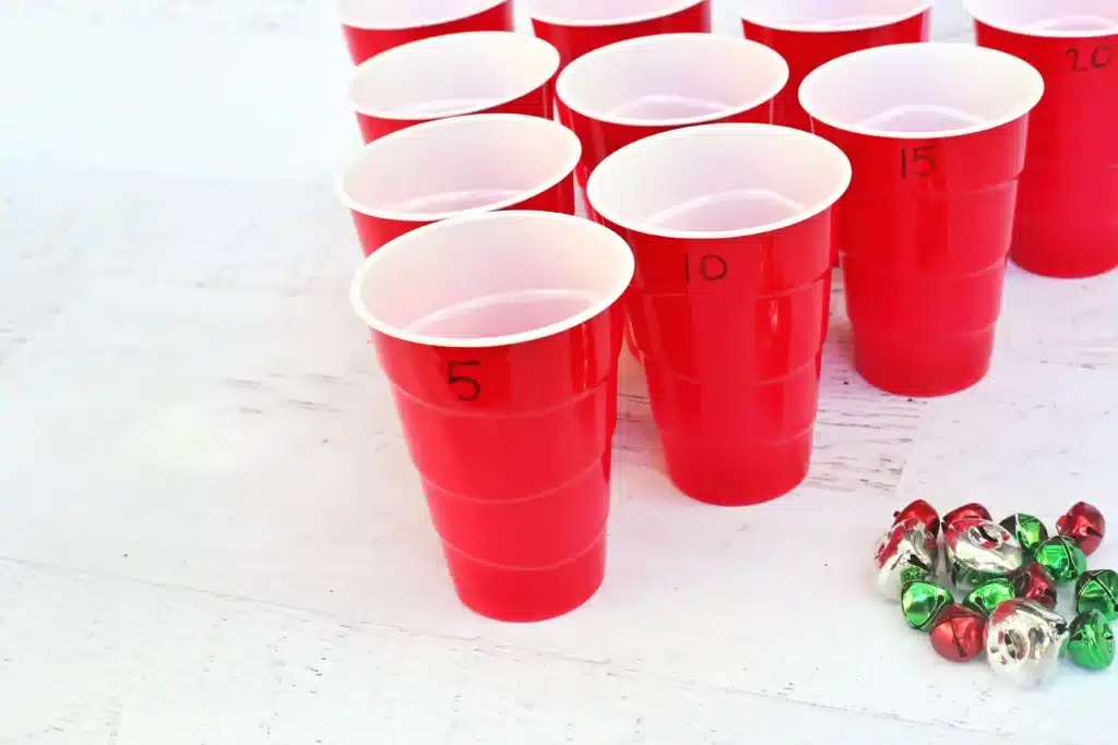 Jingle Bell Toss Reindeer Game - Cultivating Brilliant Minds red cups with numbers written on them and multicolored jingle bells