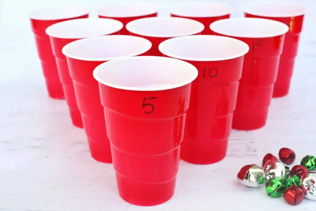 Jingle Bell Toss Reindeer Game - Cultivating Brilliant Minds red cups with numbers written on them and multicolored jingle bells