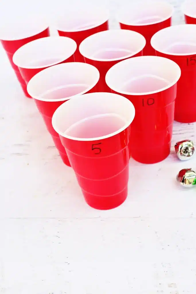 Jingle Bell Toss Reindeer Game - Cultivating Brilliant Minds red cups with numbers written on them and multicolored jingle bells