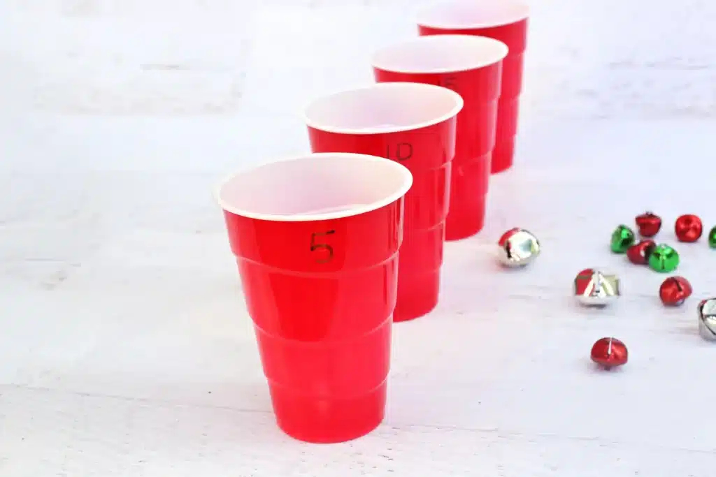 Jingle Bell Toss Reindeer Game - Cultivating Brilliant Minds red cups with numbers written on them and multicolored jingle bells